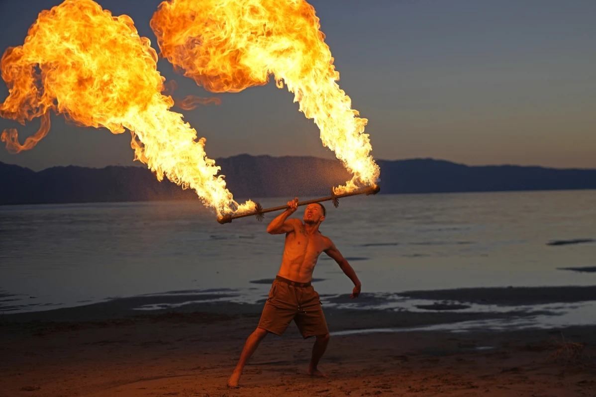 Tyler holding a blazing fire staff overhead on the Great Salt Lake shore at dusk