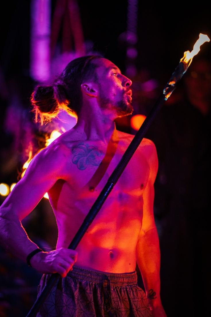 Portrait of Tyler Oborn in purple light holding a lit fire staff